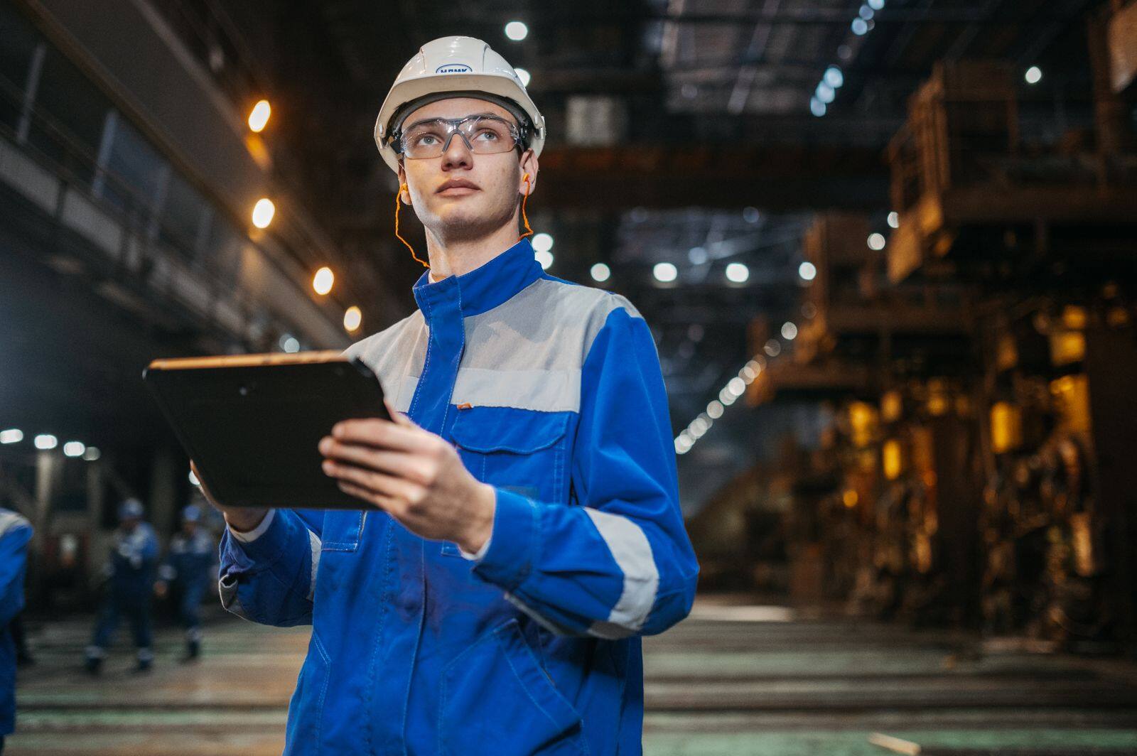 Técnico com uniforme e capacete registrando inspeção em tablet