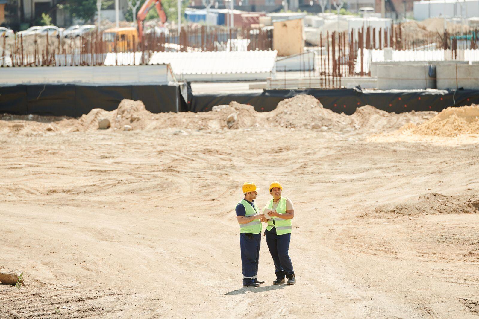 Dois trabalhadores com EPI em canteiro de terraplenagem